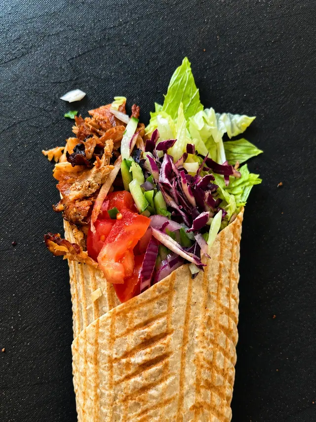 Kebab w bułce z mięsem, warzywami i sosem